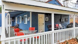 A covered porch with a table and red chairs, a door labeled "Moose Hollow," and a white picket fence. - Moose Hollow Apartment (Greenville)