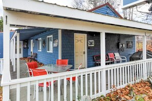 Eine überdachte Veranda mit Tisch und roten Stühlen, eine Tür mit der Aufschrift "Moose Hollow" und ein weißer Zierzaun.