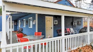 A covered porch with a table and red chairs, a door labeled "Moose Hollow," and a white picket fence. - Moose Hollow Apartment (Greenville)