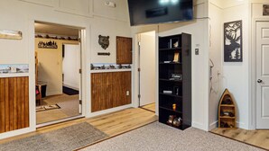 A room with a wooden floor, a black bookshelf, a mounted TV, and a door with a bear head decoration. - ATV ACCESS/WALK TO TOWN (Greenville)