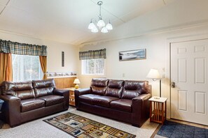 A living room with two brown leather sofas, a patterned rug, a lamp, and a framed picture on the wall.