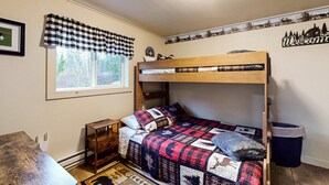A bunk bed with a checkered valance, a small wooden table, a trash can, and a welcome sign on the wall. - ATV ACCESS/WALK TO TOWN (Greenville)