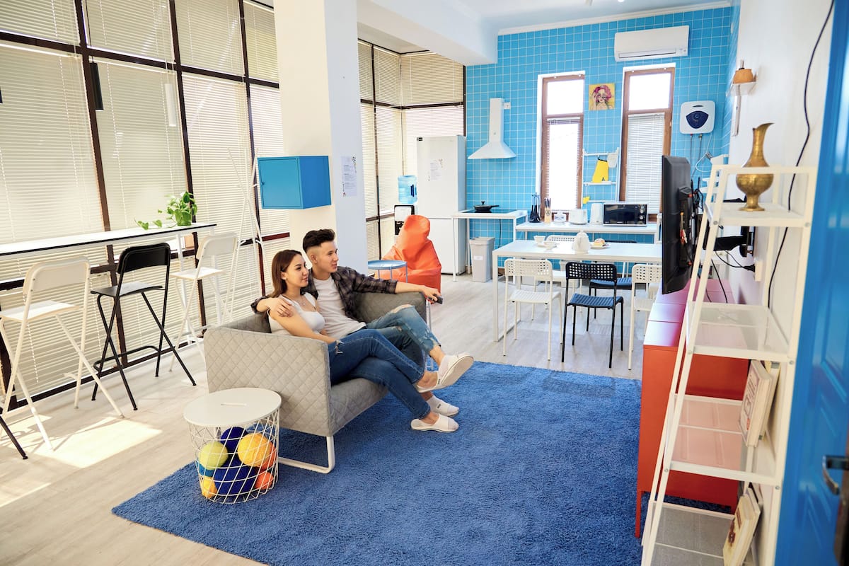 A modern living room with a sofa, a dining table, and a kitchen area in the background.