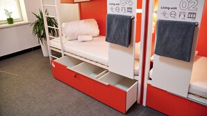 A bunk bed room with a red storage drawer, a potted plant, and a window with blinds. - Caravan  (Turkestan)