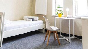 A compact room with a bed, a desk, a chair, and a window with a plant. - Caravan  (Turkestan)
