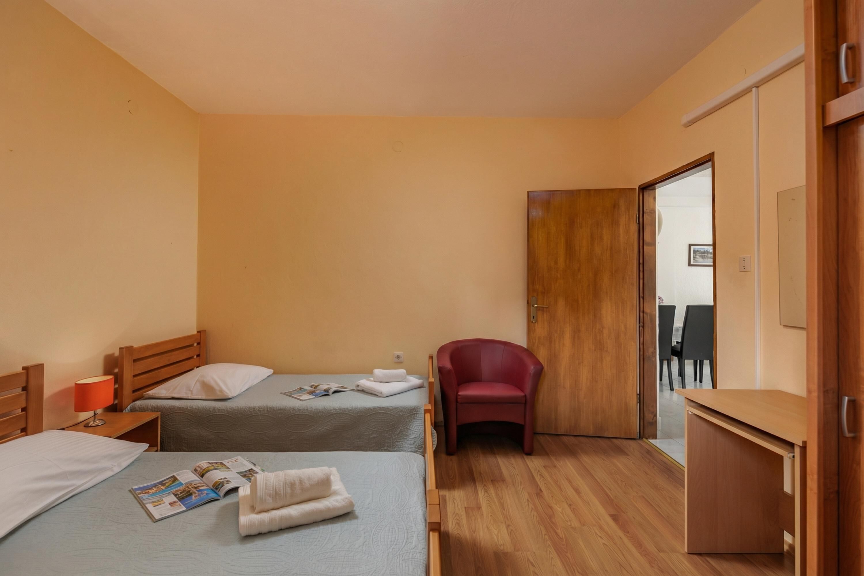 Ein Hotelzimmer mit zwei Betten, einem Schreibtisch, einem Stuhl und einem Kleiderschrank.