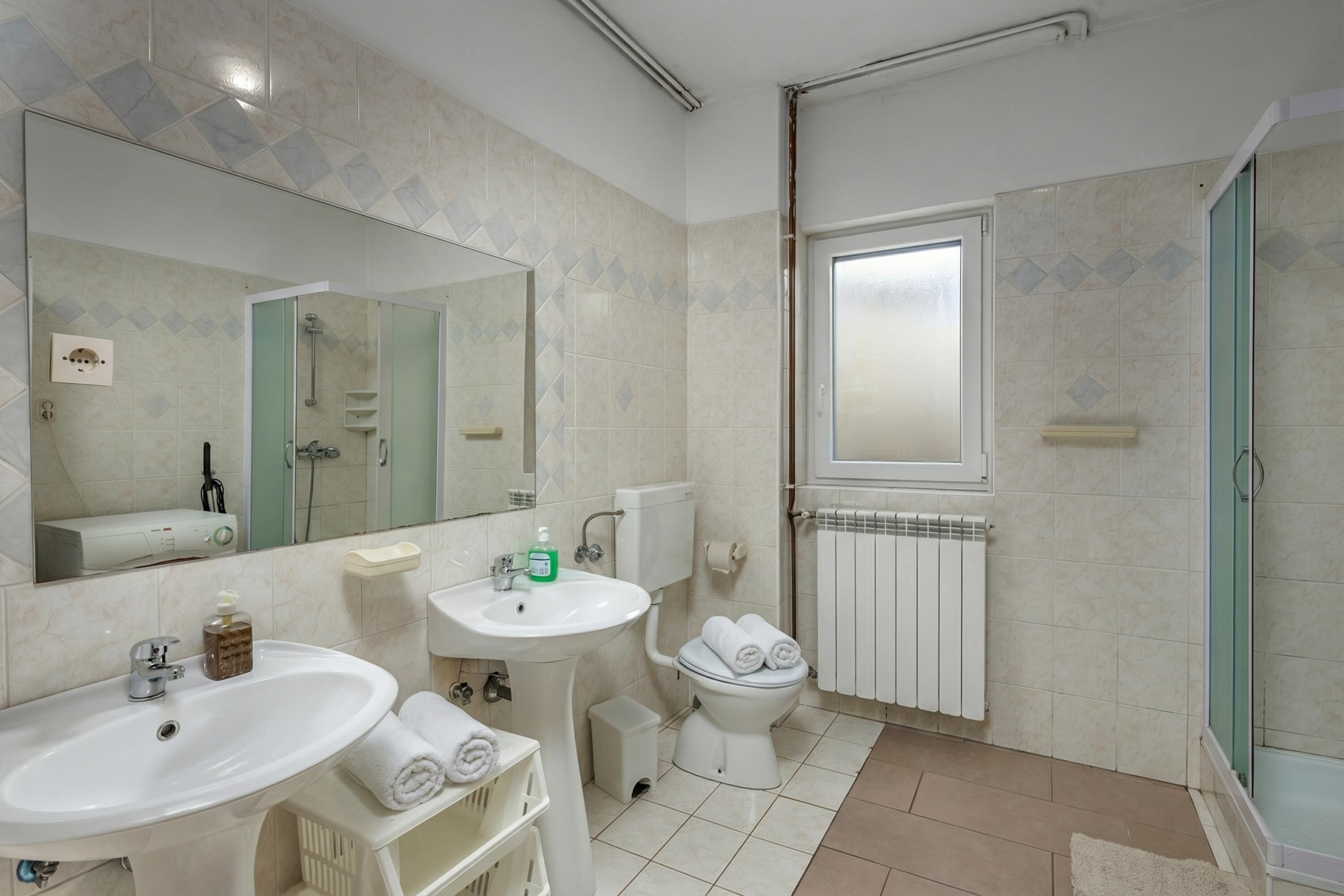Une salle de bain équipée d’un lavabo, d’un miroir, de toilettes et d’une douche.