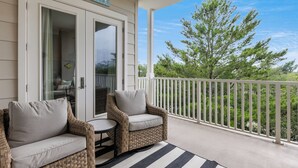 A balcony with wicker chairs and a small table, a white railing, and a view of trees. - 30A Condo + Gulf Views, Pools, Grill & Bikes (Santa Rosa Beach)