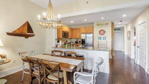 A modern kitchen with wooden cabinets, a central island, and a chandelier. - 30A Condo + Gulf Views, Pools, Grill & Bikes (Santa Rosa Beach)