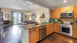 A modern kitchen with wooden cabinets, stainless steel appliances, and a central island. - 30A Condo + Gulf Views, Pools, Grill & Bikes (Santa Rosa Beach)
