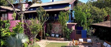 A two-story house with a patio area, surrounded by various plants and cacti.