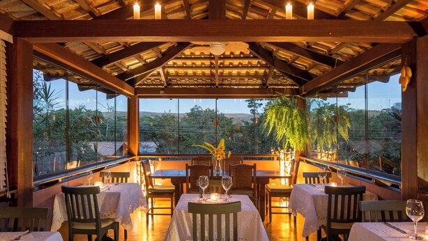 An outdoor dining area with tables and chairs, candles, and a view of the landscape. - Pousada Maya (Alto Paraíso de Goiás)