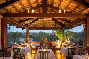 Un área de comedor al aire libre con mesas y sillas, velas y vistas al paisaje.