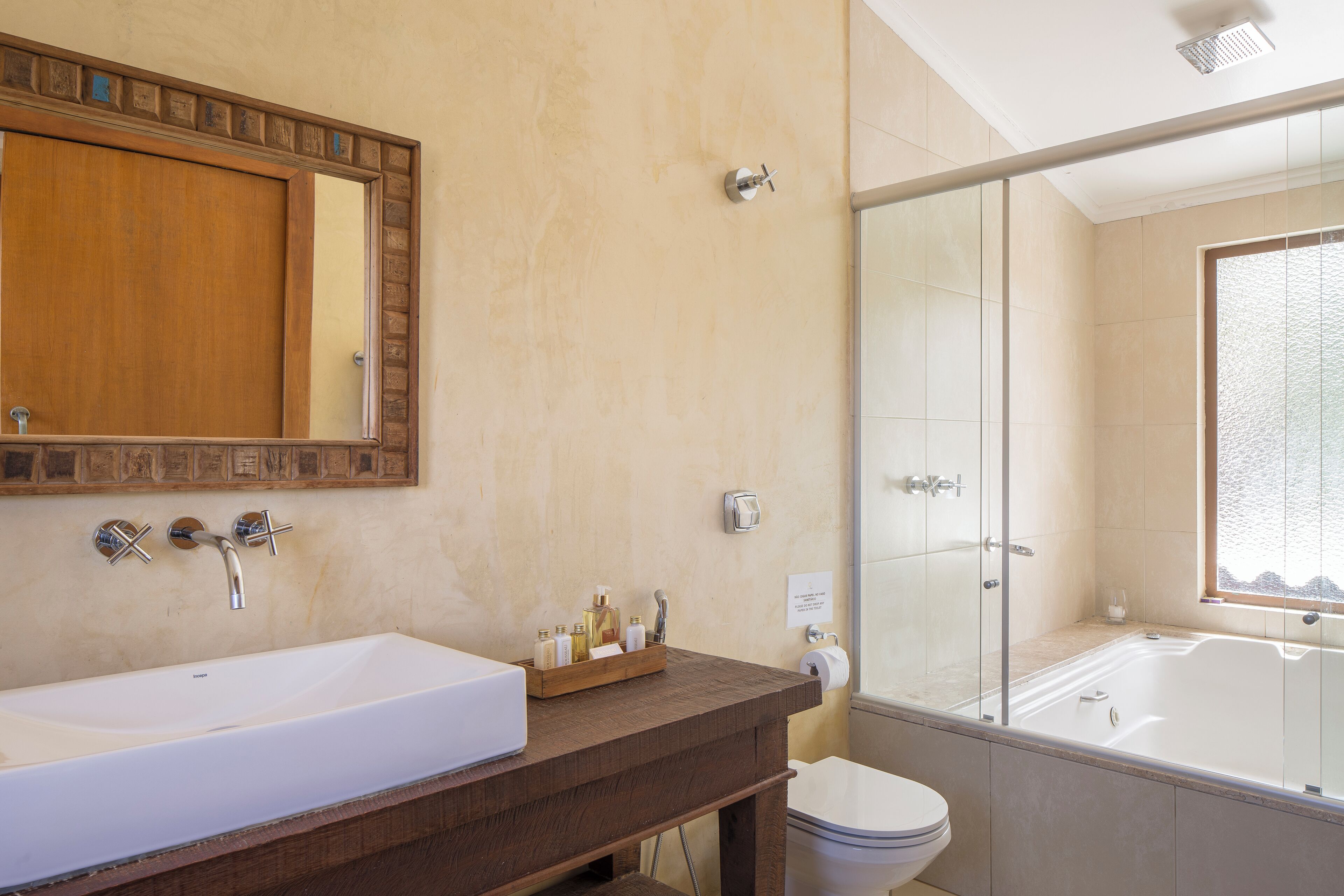 Une salle de bain avec un grand lavabo blanc, un meuble-lavabo en bois, une cabine de douche en verre et un grand miroir.
