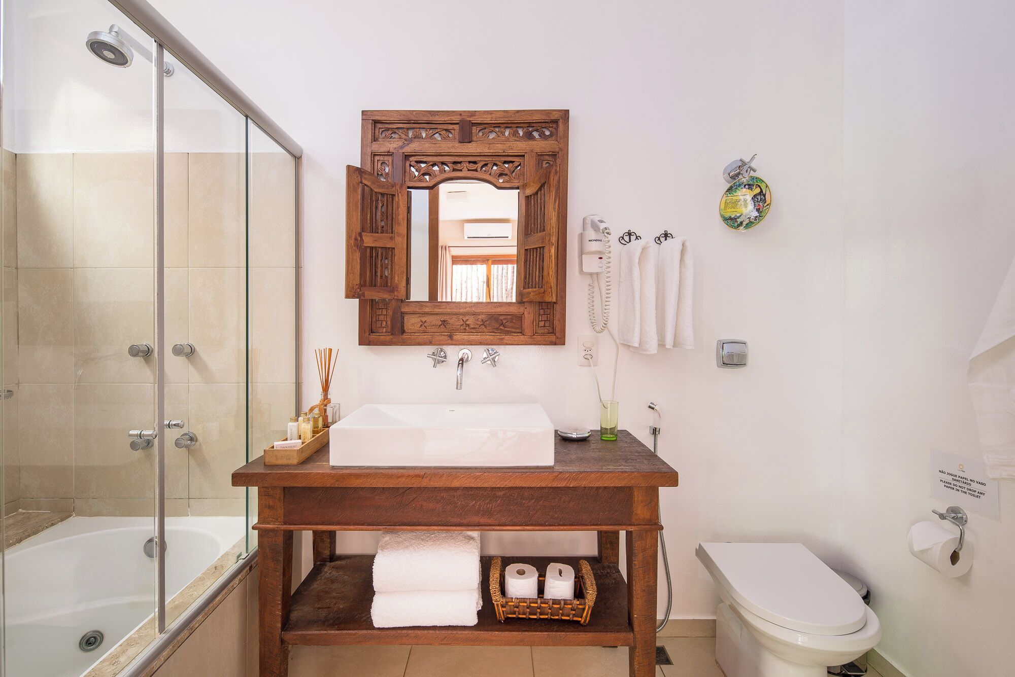 A bathroom with a glass shower enclosure, a wooden vanity with a sink, a mirror, and a toilet.