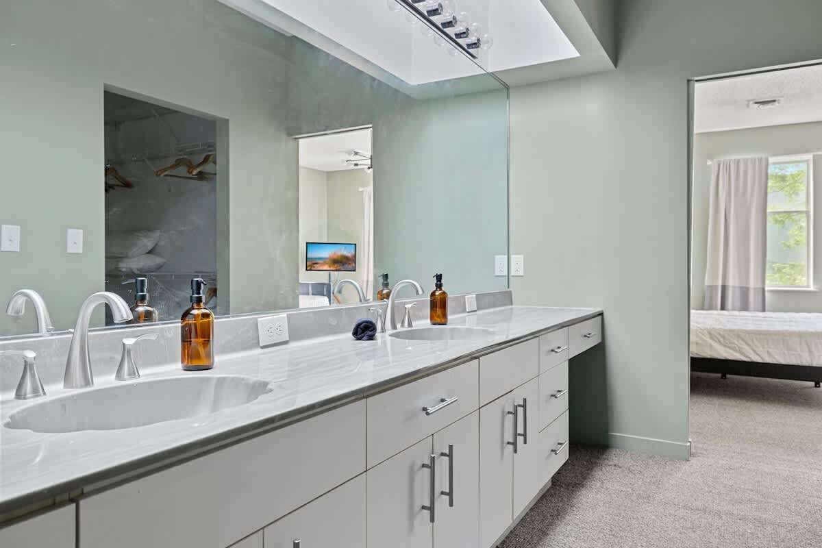Une salle de bain moderne avec un grand miroir, deux lavabos et une douche à l’italienne.