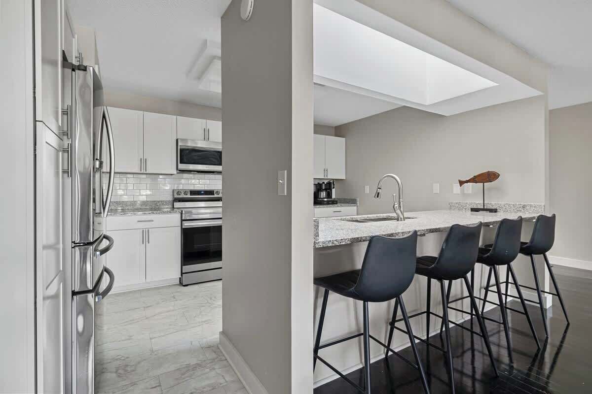 Eine moderne Küche mit Edelstahlgeräten, einer Marmorarbeitsplatte und einer Bar mit Hockern.