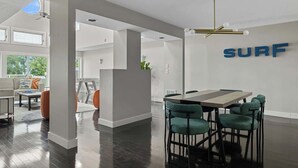 Un intérieur moderne avec un coin repas, le mot « SURF » bien visible sur le mur, et un escalier menant à un autre niveau.