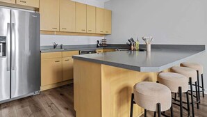 Una cocina moderna con una isla central, nevera de acero inoxidable y armarios de madera.