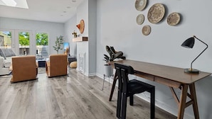 Una sala moderna con una mesa de comedor de madera, dos sillones marrones, una silla negra y una lámpara de pie negra.