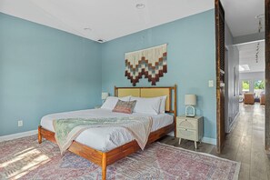 Relax in this serene bedroom with a large bed, decorative wall hanging, and cozy bedside table.