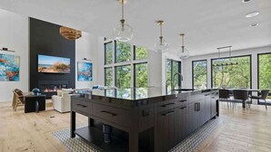 A modern kitchen with a central island, large windows, and a fireplace. - Juniper Presents: Contemporary 26-Acre Estate, Private Beach, Pool (Stevensville)
