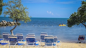 Ein Strand mit blauen Liegestühlen und einem Kajak im Wasser.