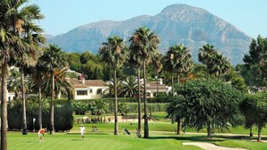 A golf course with palm trees, a mountain in the background, and houses in the distance. - Villa Bibi with Spectacular Sunset and Views (Javea)