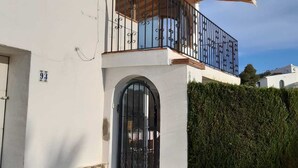 A two-story house with a balcony, a stone base, and a black gate. - Villa Bibi with Spectacular Sunset and Views (Javea)