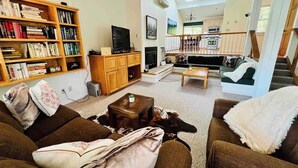 A spacious living room with a large bookshelf, a television, and a cozy seating area.
