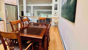 A dining area with a wooden table and chairs, a chandelier, and a painting on the wall.