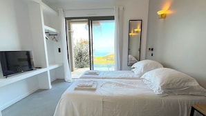 A bedroom with a bed, a TV, a mirror, and a view of the outdoors. - Villa San Joseph (Cargès)