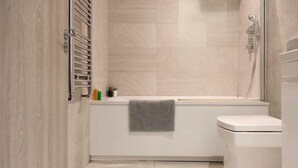 Een moderne badkamer met een bad, toilet en douche.