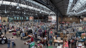 Een grote overdekte markt met talloze kraampjes en een hoge ruimte met metalen balken.