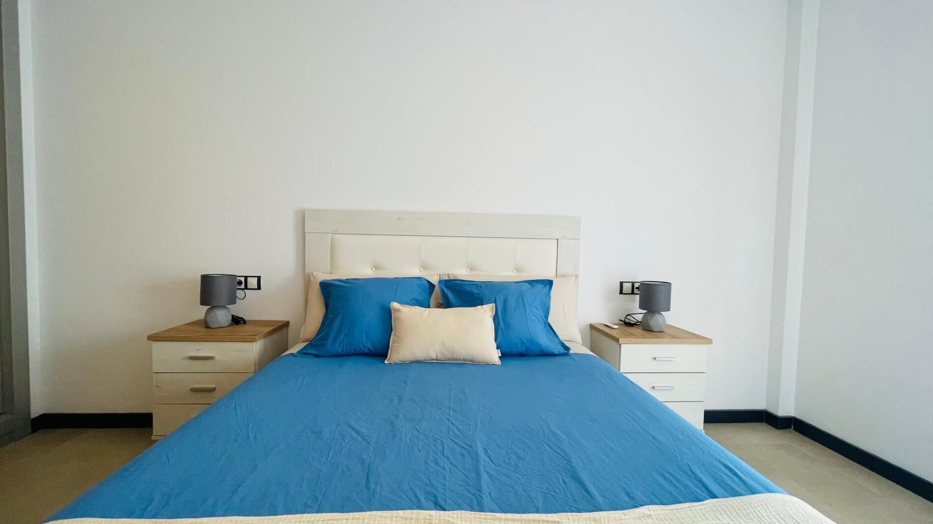 A bedroom with a large bed, two bedside tables, and a headboard.