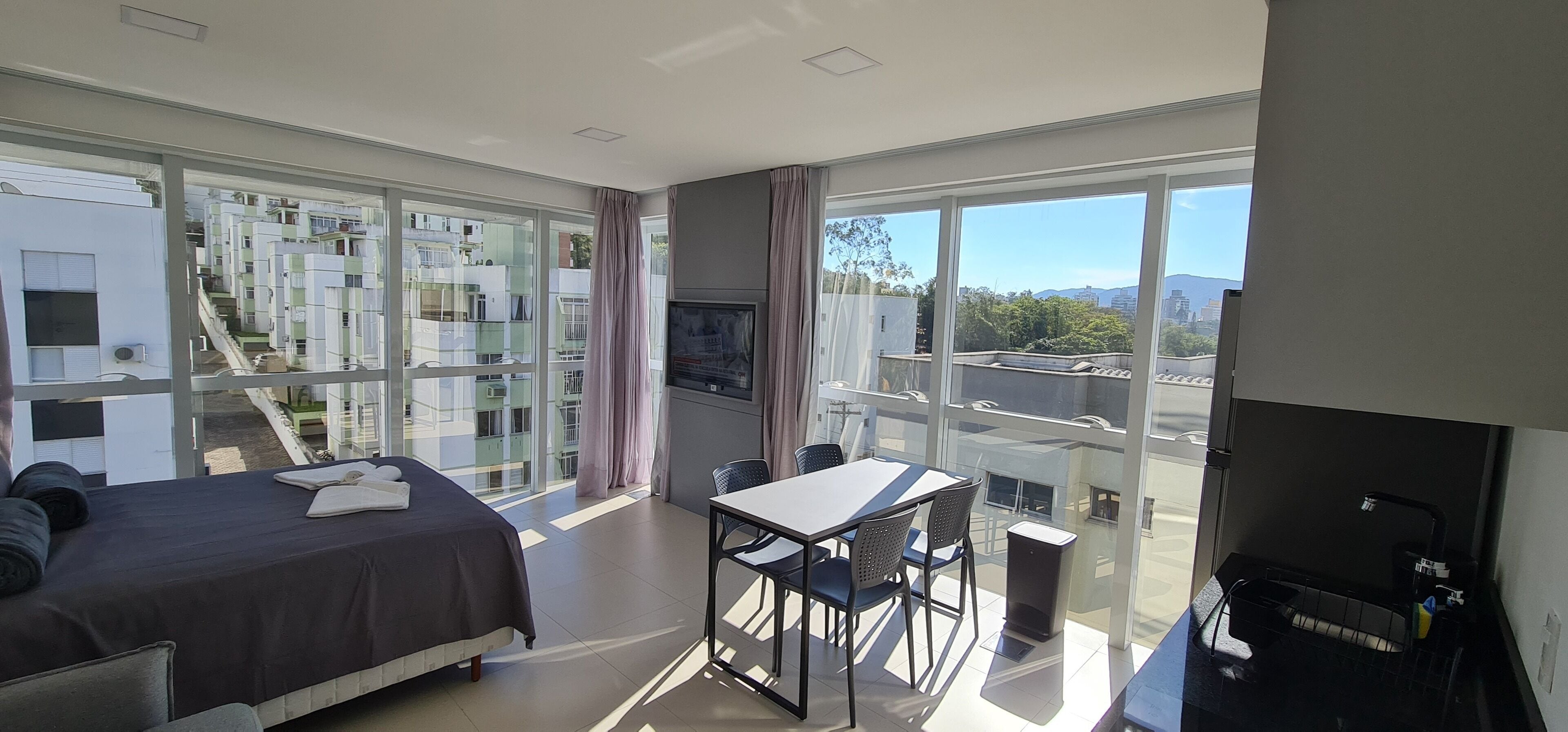Une chambre d’hôtel moderne dotée d’un grand lit, d’une table à manger et d’un balcon offrant une vue sur la ville.