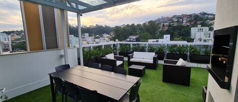 Eine Dachterrasse mit Essbereich, Gartenmöbeln und Blick auf die Stadtlandschaft.