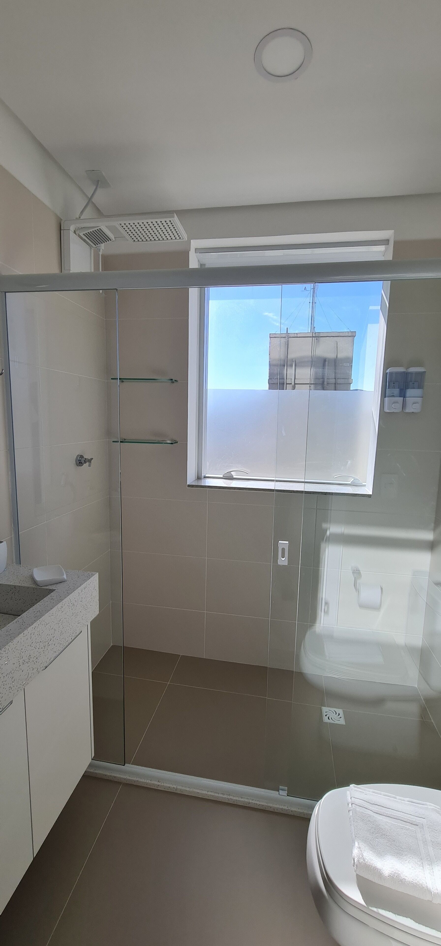 Un baño moderno con cabina de ducha de vidrio, inodoro y lavamanos con encimera.