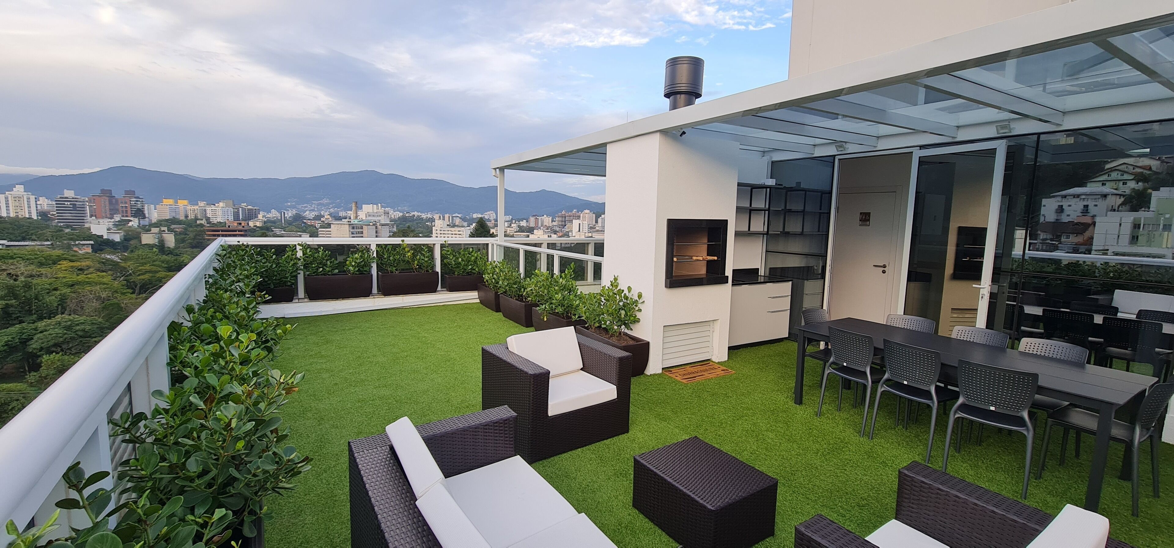 Eine Dachterrasse mit Gartenmöbeln, einer Glasveranda und Blick auf die Stadt.