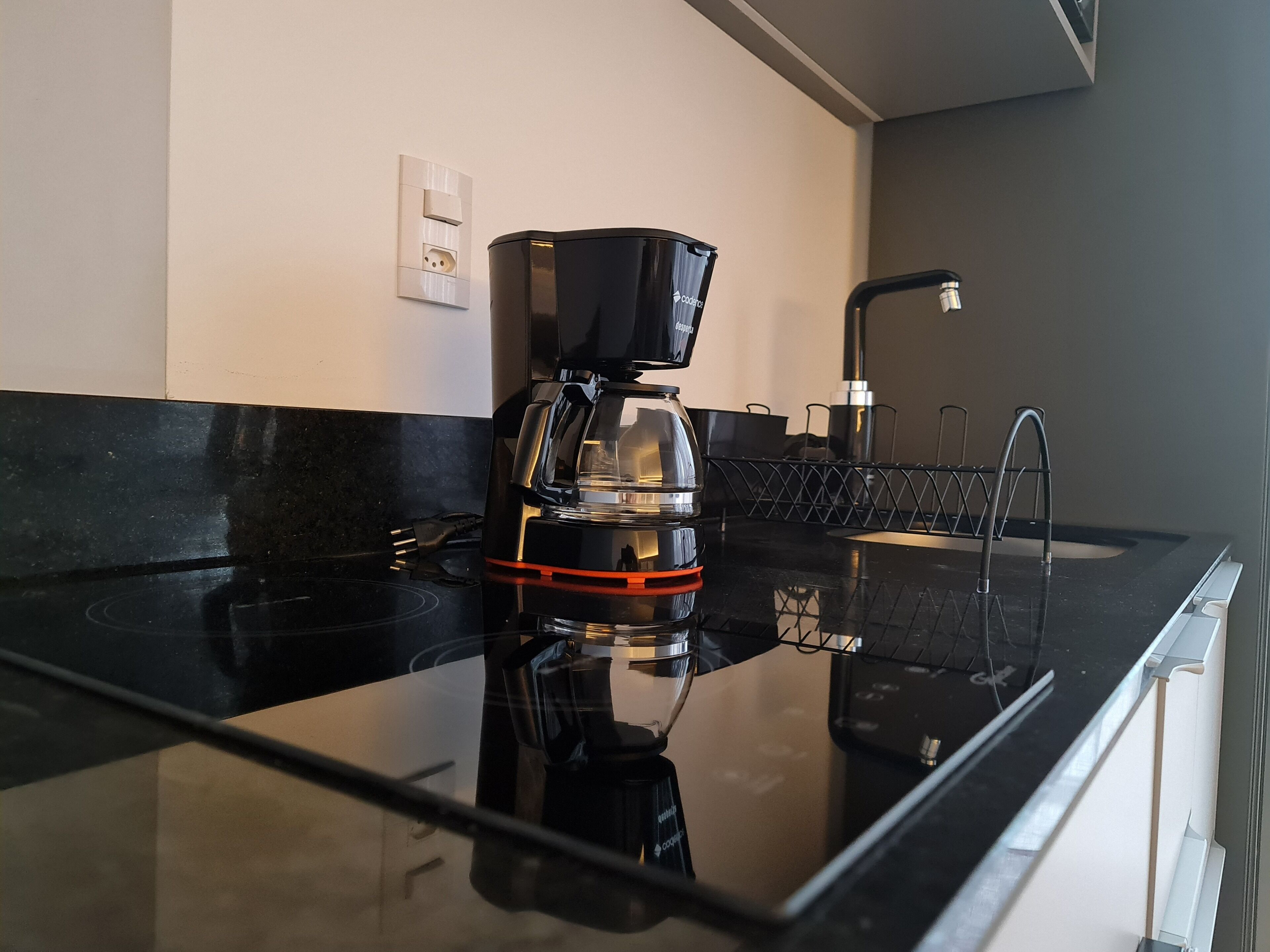 Una cucina moderna con un piano di lavoro nero, una moka e un lavandino.