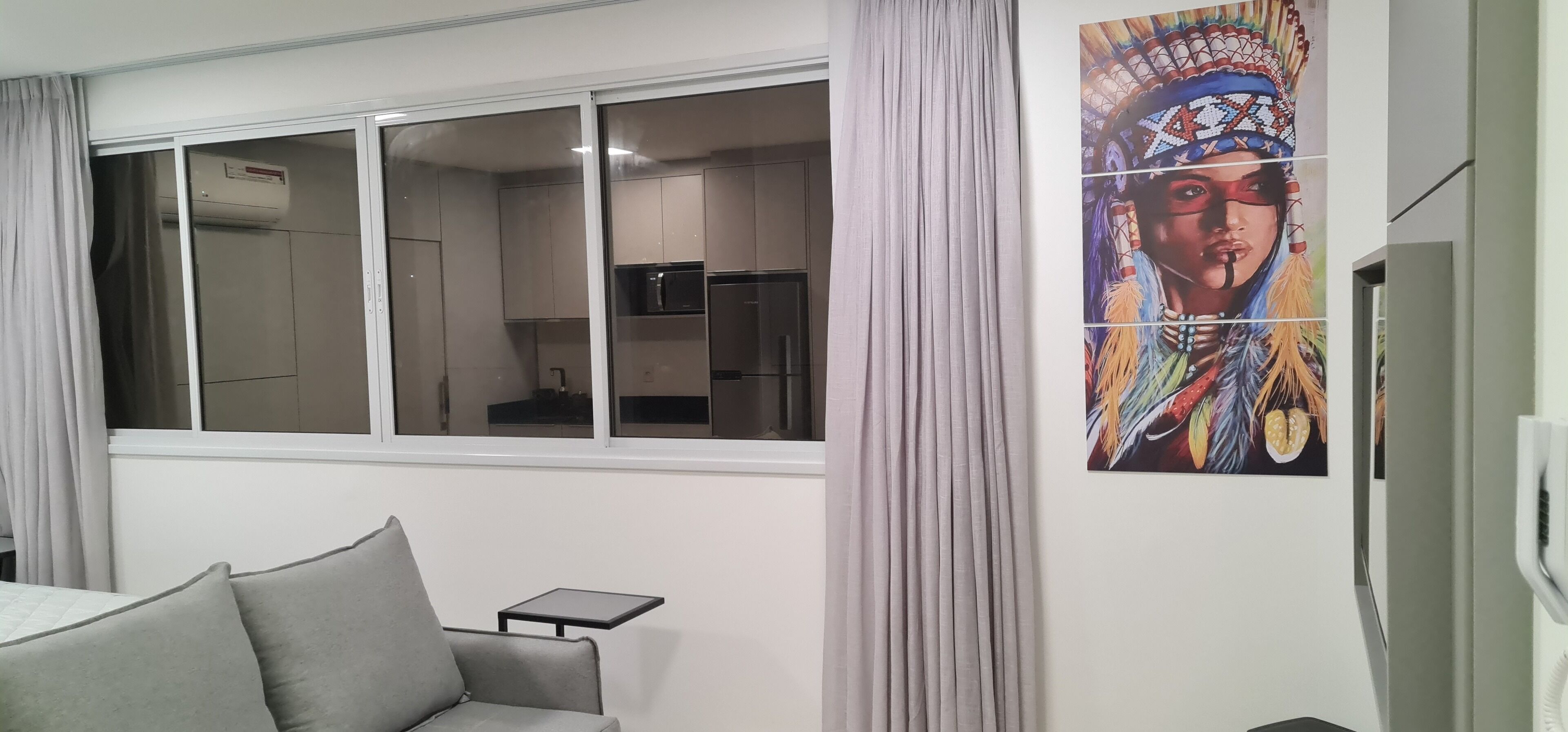Una sala de estar moderna con un sofá, una mesita y un amplio ventanal con cortinas.