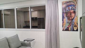 Una sala de estar moderna con un sofá, una mesita y un amplio ventanal con cortinas.