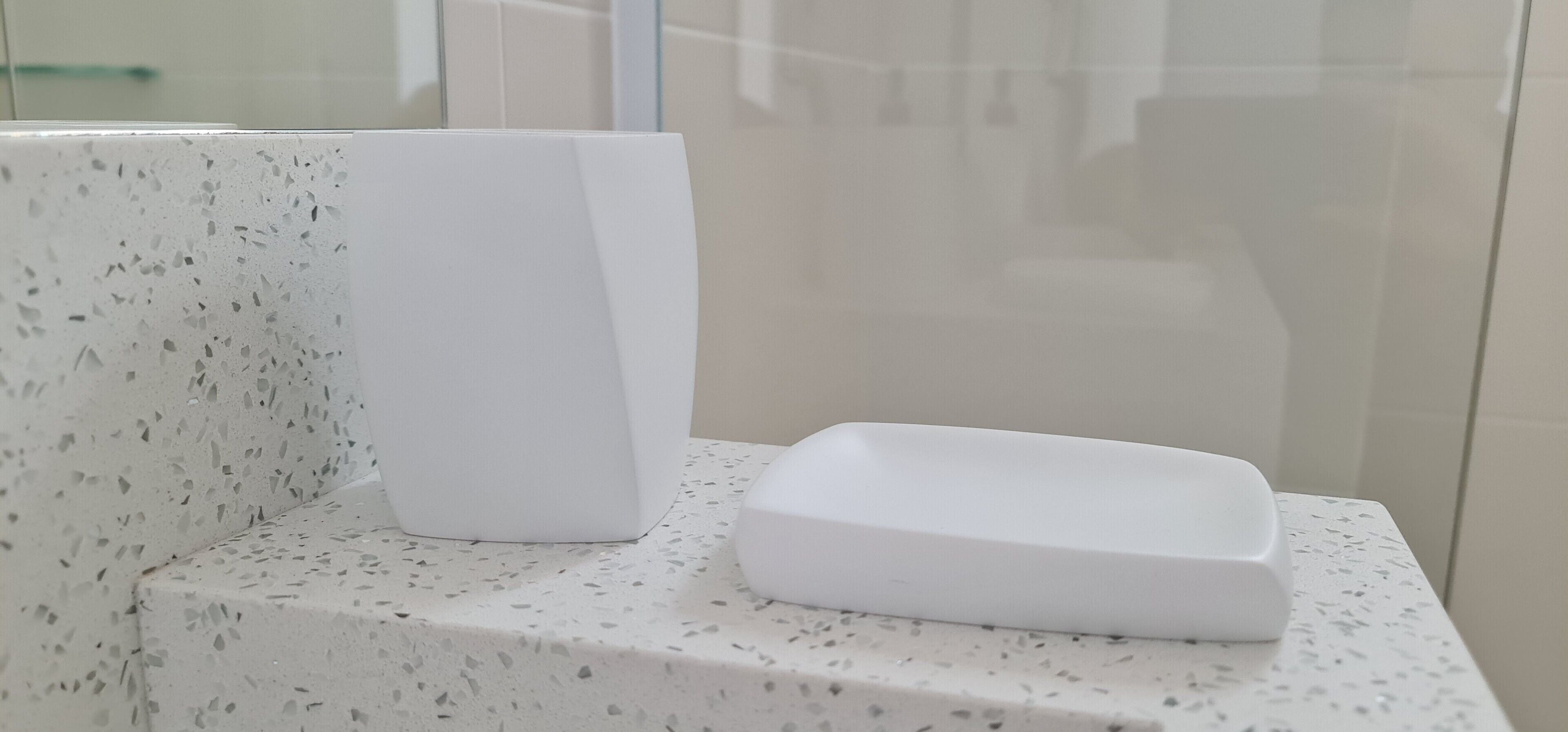 A bathroom with a white countertop and a glass shower enclosure.