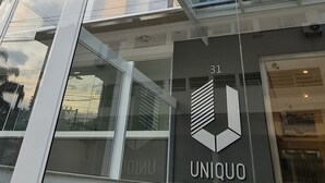 Un bâtiment moderne doté d’une façade en verre et d’un logo sur lequel on peut lire « UNIQOO ».