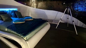 Ein modernes Schlafzimmer mit einem gebogenen Bett, blauer Bettwäsche und einem Kopfteil mit blauer Beleuchtung.