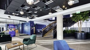 A modern lobby with a staircase, seating areas, and a reception desk. - Aspen House - Campus Accommodation (Dublin)