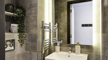 Un baño moderno con un lavamanos blanco, grifería cromada y un espejo grande.
