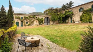 A courtyard with stone walls, a stone bench, and two chairs. - Dependance a Baglio il Corvo by Wonderful Italy (Geraci Siculo)