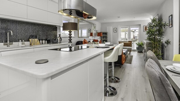 A modern kitchen with a central island, white cabinetry, and a black backsplash.