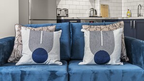 A blue sofa with patterned cushions in a modern kitchen setting. - Buzzing Brighton Apartment 1 | By My Getaways (Brighton)
